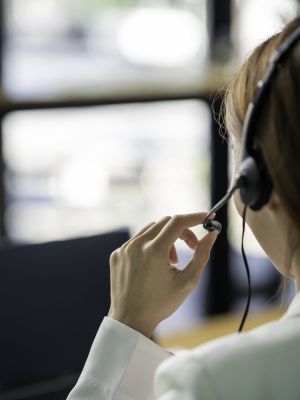 Friendly female helpline operator with headphones in call center